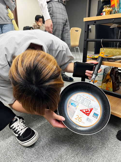 フライパンをマジマジと見る社員の画像