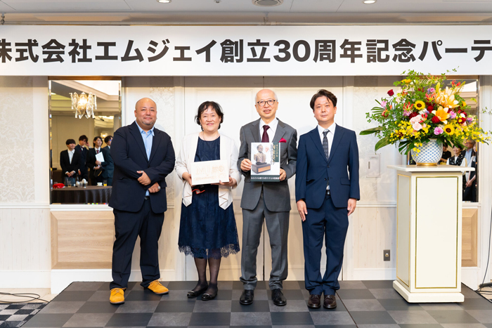 記念写真をとる社長ご夫婦と社員