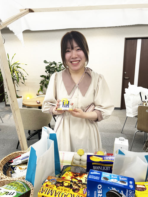 会場でお菓子を持ってポーズをとる社員