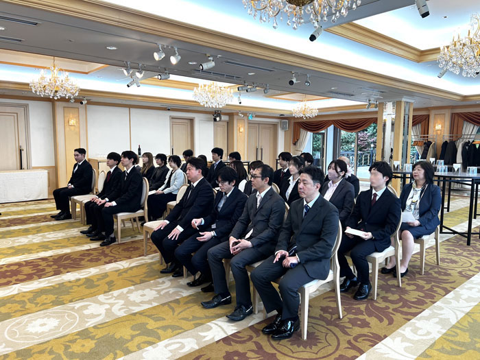会場の椅子に座って式に臨む社員
