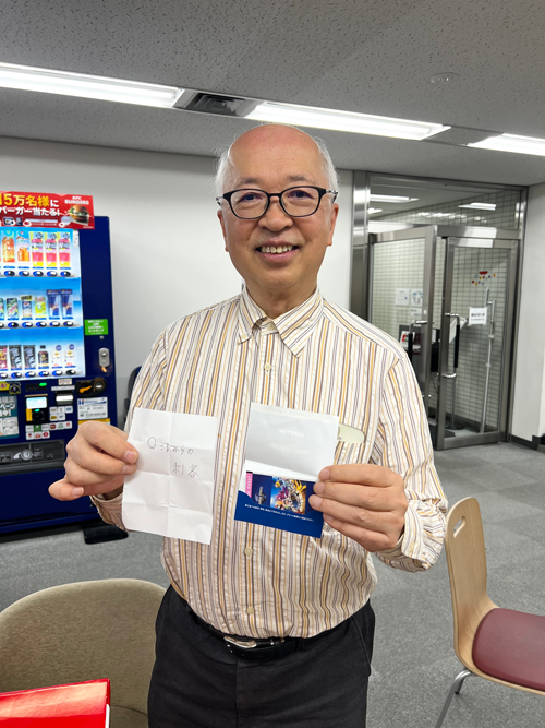 当選者の名前と賞品を手に取る社長